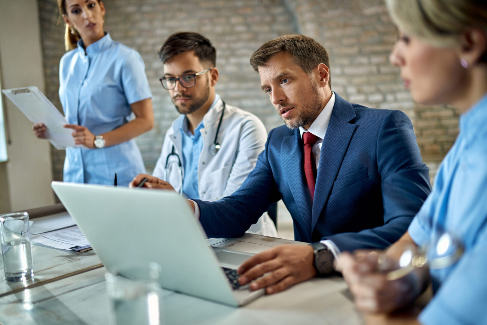 A group of people sitting around a table with laptops.